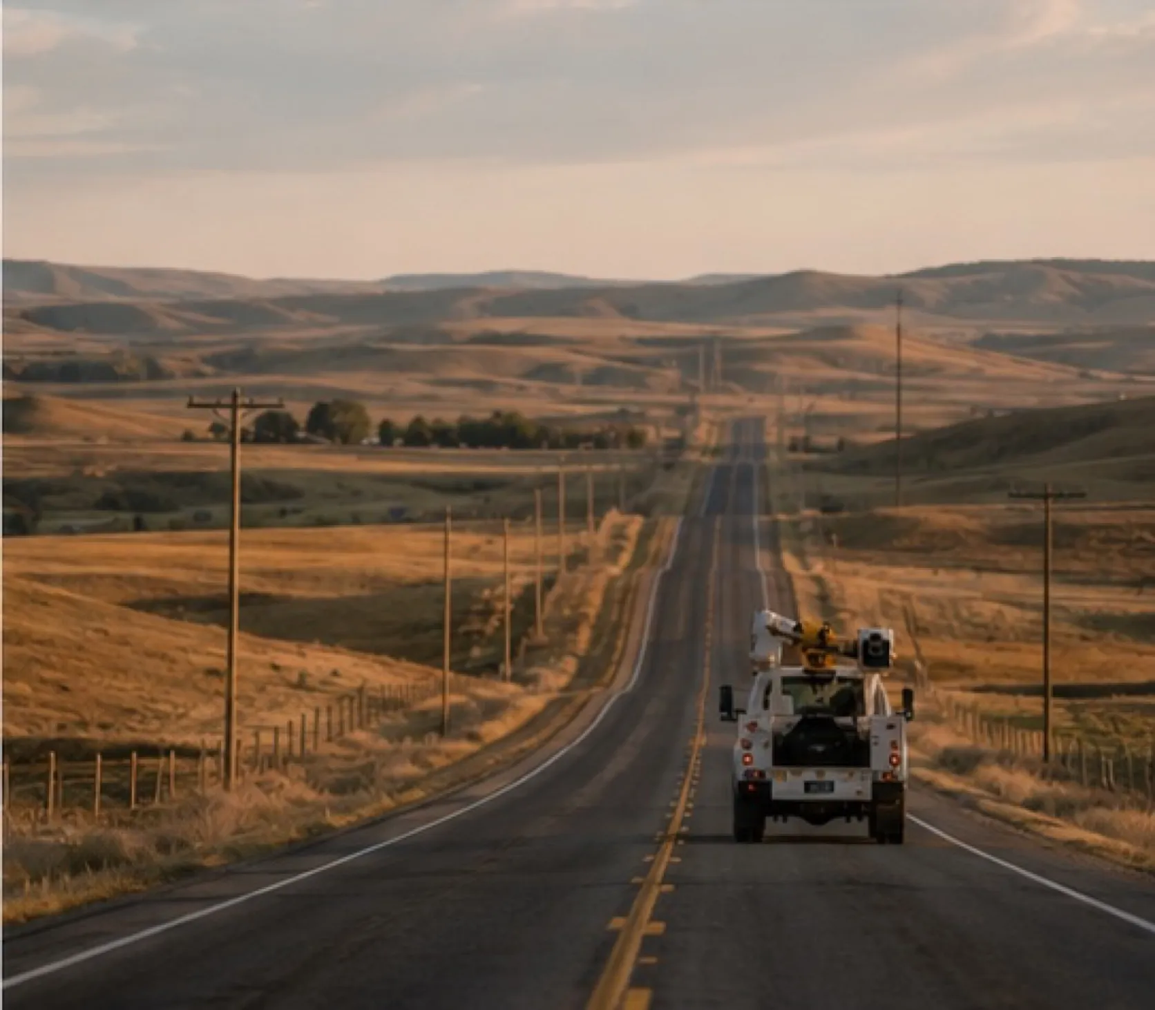 A utility truck far down a long, empty rural road.